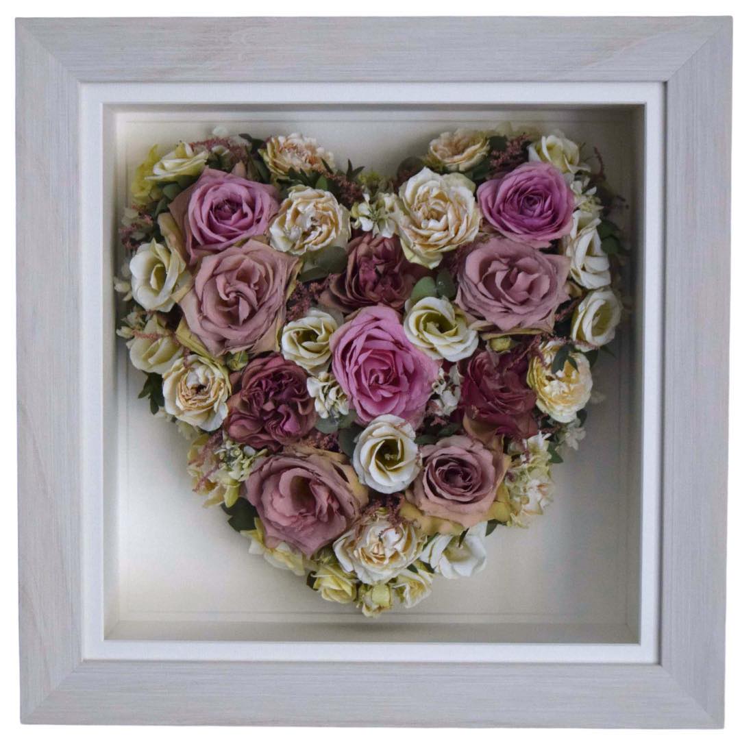 Heart shaped preserved pink bridal bouquet displayed in a white frame