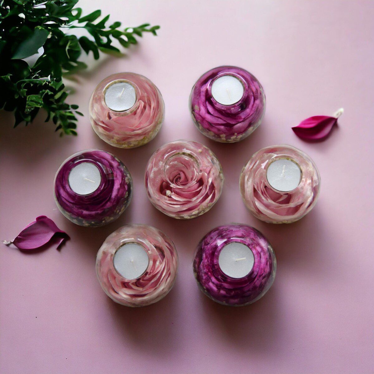 A set of pink remembrance resin tealight holders each with a preserved pink rose