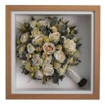 White wedding bouquet preserved and displayed diagonally in a square oak box frame