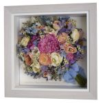 Preserved pink and lilac pastel peony, rose, daisy and sweet pea bridal bouquet in a white wood box frame
